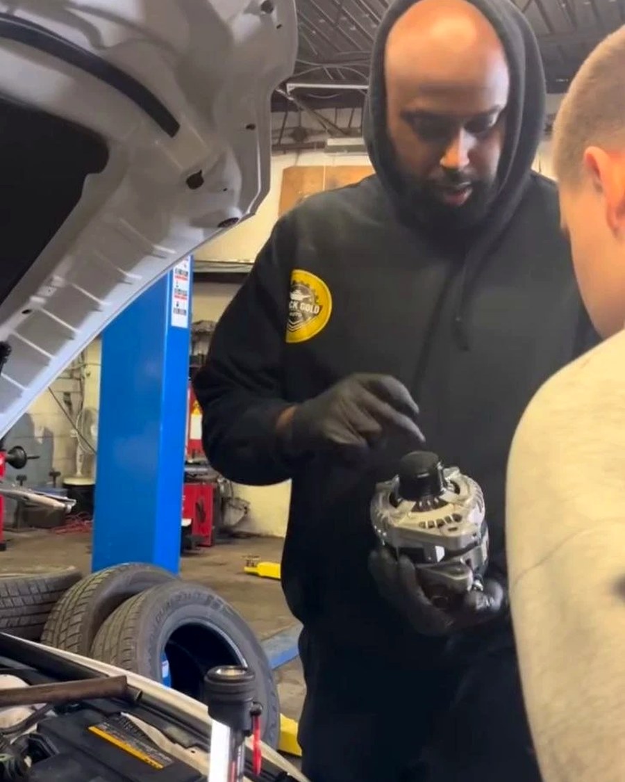 Abdul explaining an alternator to a youth trainee at Black Gold Auto
